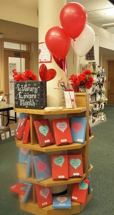 valentine's day display with heart shaped balloons and greeting cards on shelves in an office