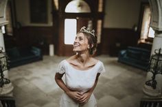 a woman wearing a tiara standing in an old building looking up at the sky