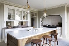 a large kitchen island with stools in front of it and two lights hanging from the ceiling