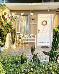 a house with potted plants in front of it and a white door on the side