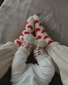 a baby laying on top of a bed wearing white pants and red socks with hearts