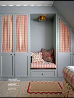 a room that has some gray cabinets and pillows on the floor in it, with pink curtains