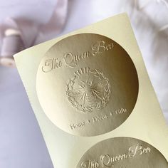 two gold foiled cards with the queen bee logo on them