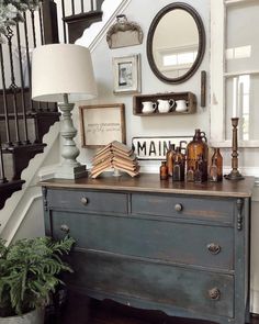 an old dresser with books and other items on it in front of a stair case