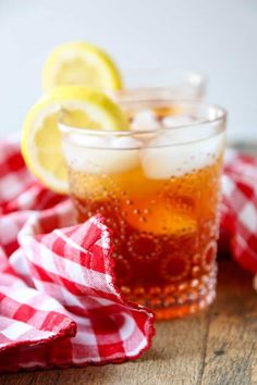 two glasses filled with ice and lemons on top of a red checkered cloth