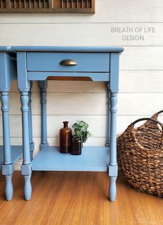 a blue table with a basket and vases on the top, next to it