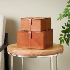 two brown leather boxes sitting on top of a wooden table next to a white chair