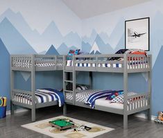 two bunk beds in a room with mountains painted on the wall and rug underneath them