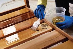 a person in blue gloves painting wooden furniture