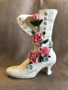 a white boot with pink flowers on the side and name written on the heel, sitting on a brown background