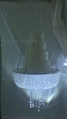 a chandelier hanging from the ceiling in front of a white curtain with lights on it