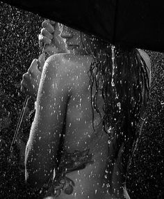 black and white photograph of a woman under an umbrella with water splashing on her