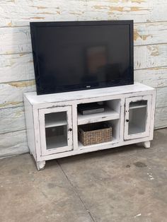 a white entertainment center with glass doors and baskets in front of a brick wall behind it