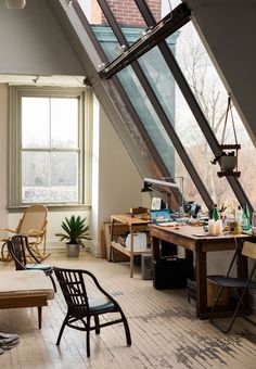 an attic office with lots of clutter on the desk and chairs in front of it