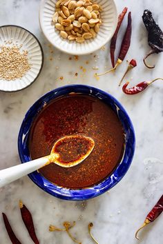 a bowl filled with sauce next to two bowls full of chili peppers and other ingredients