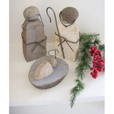 three stone salt and pepper shakers on display with holly branches in the foreground