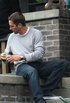 a man sitting on the steps looking at his cell phone and holding something in his hand