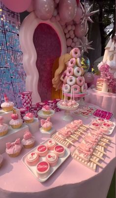 a table topped with lots of pink and white desserts