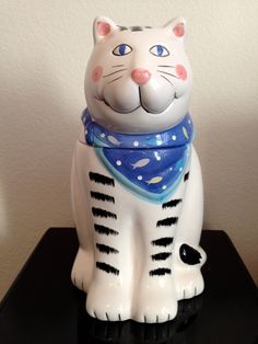 a ceramic cat with a blue bandanna around it's neck sitting on a table