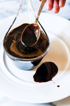 a person pouring sauce on top of a white plate