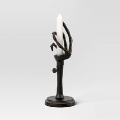 a black candle holder with two white candles in the shape of an arm and legs