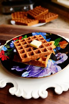 two waffles on a plate with butter and syrup sitting next to each other