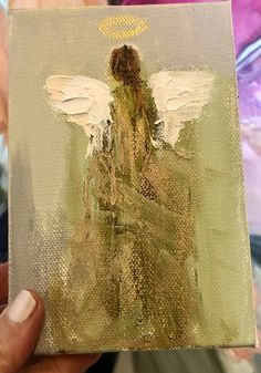 an angel painting is being held up by someone's hand