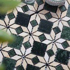 a green and white tiled floor next to a vase with flowers on top of it