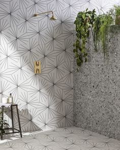 a bathroom with cement tiles and plants on the wall, along with a wooden stool