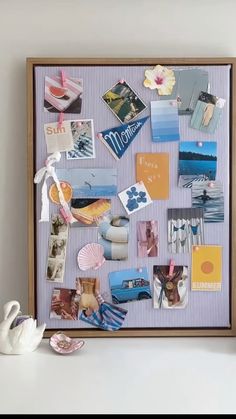 a white swan sitting on top of a table next to a wooden frame filled with pictures