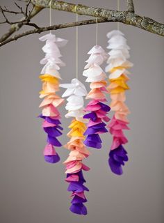 colorful paper flowers hanging from a tree branch