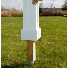 a person holding onto a tall white object in the grass