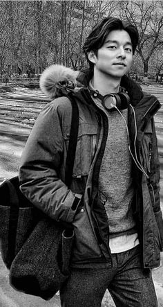 black and white photograph of a man walking in the park with earbuds on