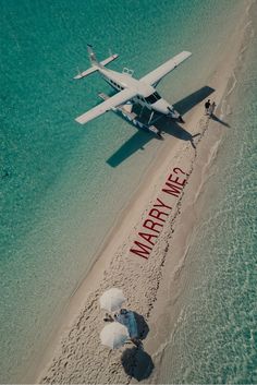 an airplane is flying over the beach with people under umbrellas in the sand and water