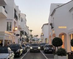 several cars parked on the side of a street next to tall buildings and palm trees