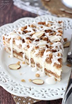 a piece of cake with white icing and almonds on a plate next to a fork