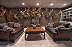 a living room with couches and deer heads on the wall