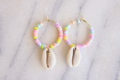 "Sunset Breeze Pastel Beaded Shell Hoop Earrings 3mm Pastel rainbow vinyl Heishi beads beaded on 20mm gold stainless steel hoops finished with cowrie shells These earrings are approximately 1.5 inches long & 1\" wide The perfect mini hoops for summer! Handmade with love by Amanda **please read my shop's policies** Thanks for viewing! 🐚" Trendy Hoop Earrings With Round Beads For Beach, Trendy Beach Hoop Earrings With Round Beads, Colorful Handmade Hoop Earrings For Beach, Colorful Beaded Small Hoop Earrings For Beach, Summer Rainbow Heishi Beads Jewelry, Handmade Shell Hoop Earrings For Beach, Summer Beach Shell Hoop Earrings, Handmade Shell-shaped Hoop Earrings For Summer, Rainbow Vinyl