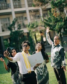 three people are standing in the grass and one person is holding up a piece of paper