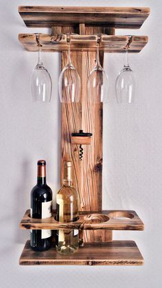 a wooden shelf with wine glasses, bottles and two wine glasses hanging from it's sides