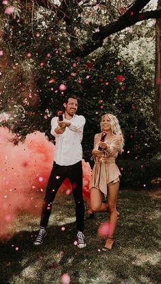 a man and woman standing in the grass with confetti