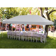 a large white tent set up with tables and chairs for an outdoor party in the grass