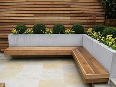 a wooden bench sitting next to a planter filled with yellow flowers