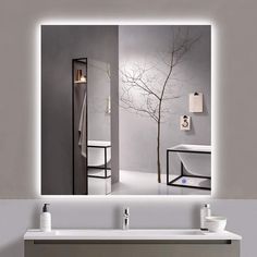 a bathroom sink with a mirror above it and a tree in the reflection on the wall