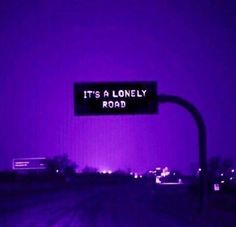 it's a lonely road sign lit up in the dark purple light at night