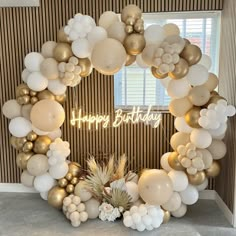 a happy birthday balloon arch with white and gold balloons, pineapples and palm leaves