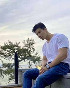 a young man sitting on top of a cement wall