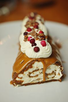 a piece of cake on a white plate with chocolate and cherries in the middle