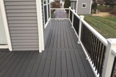 a wooden deck with white railings and gray siding