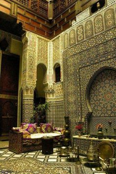 the interior of an ornately decorated building with intricate tilework and flowers in vases